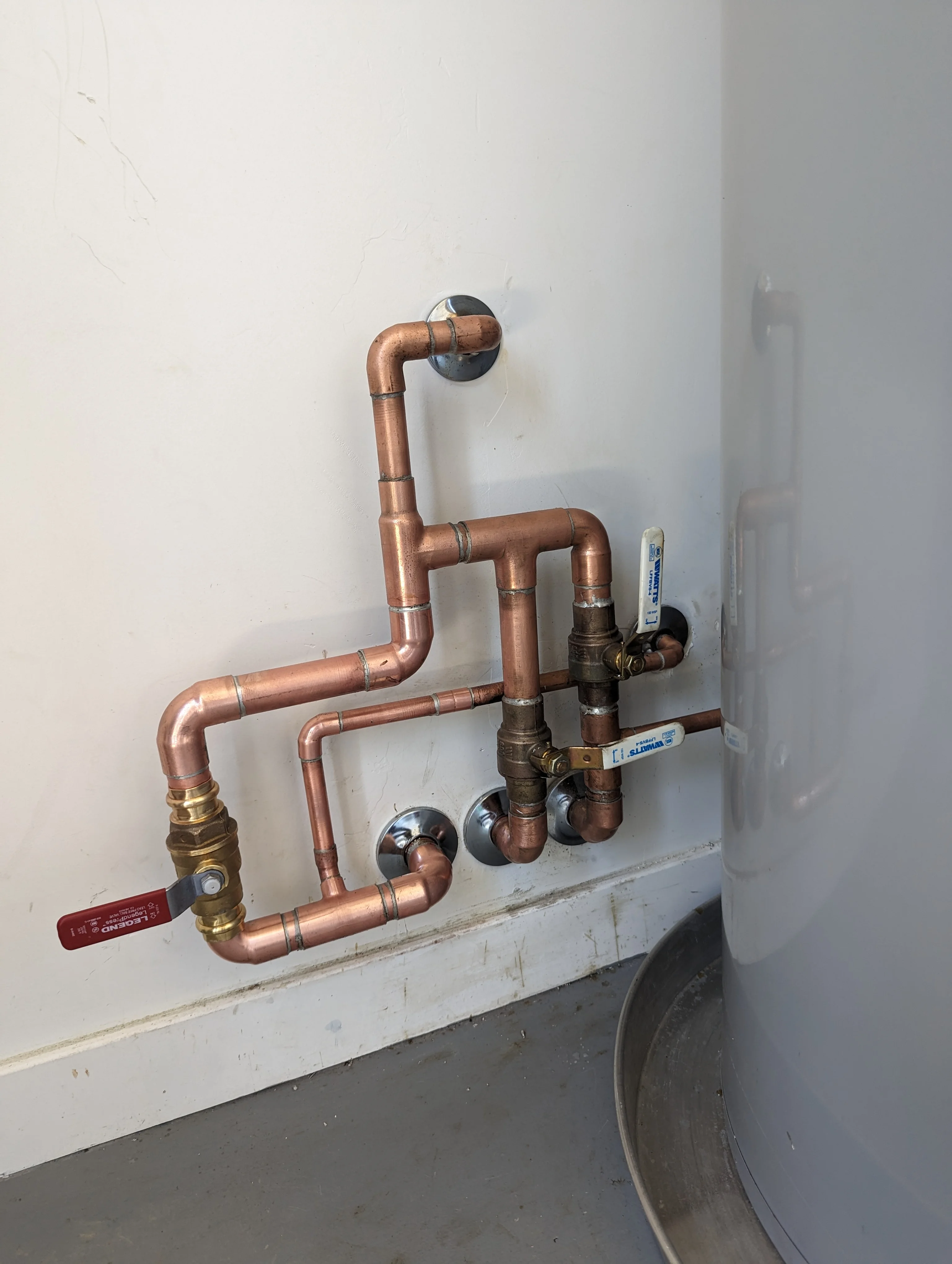 Copper pipe manifold with ball valves and brass fittings mounted on white wall
