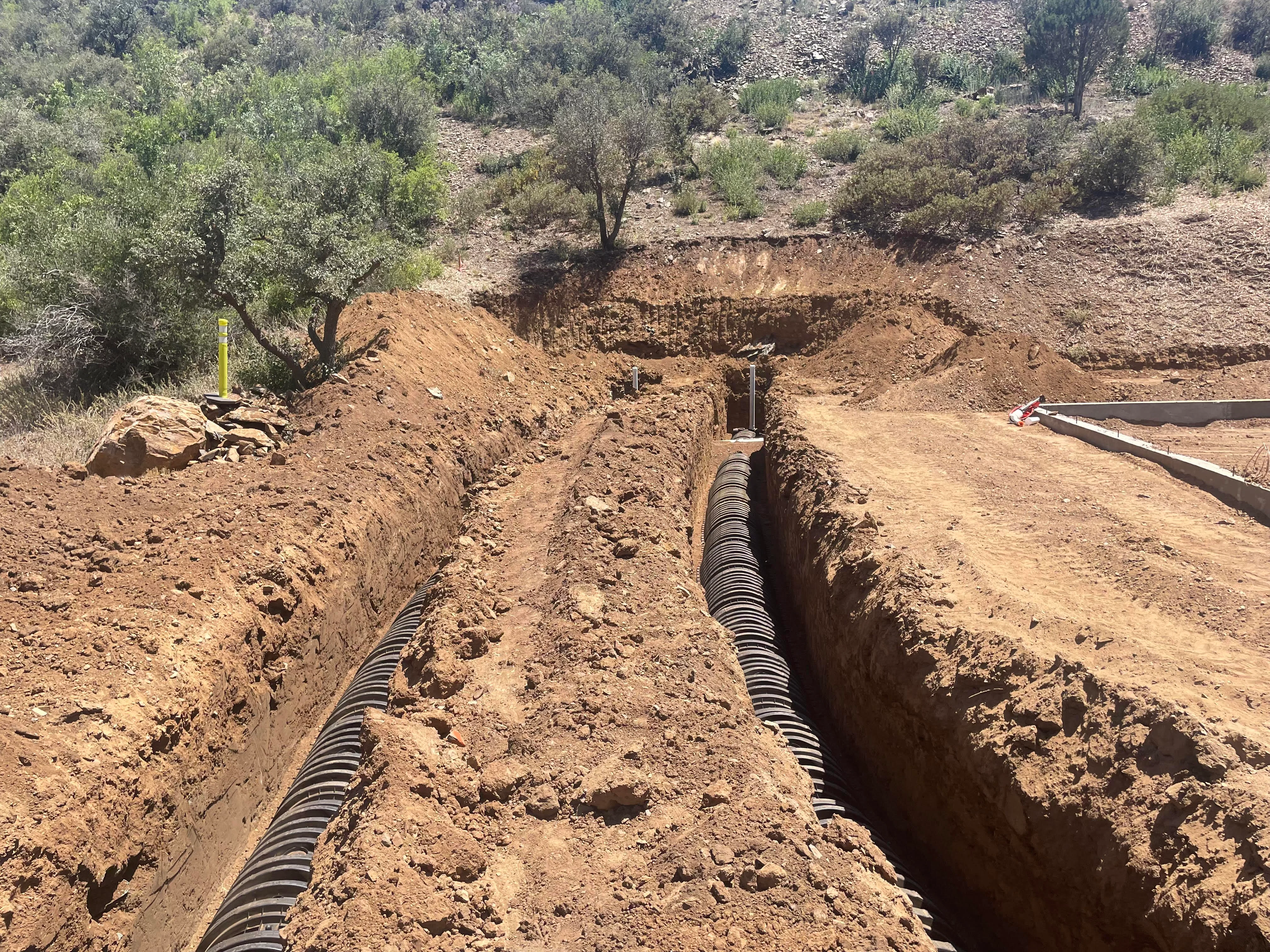 Dual corrugated drain pipes in excavated trenches for septic leach field installation