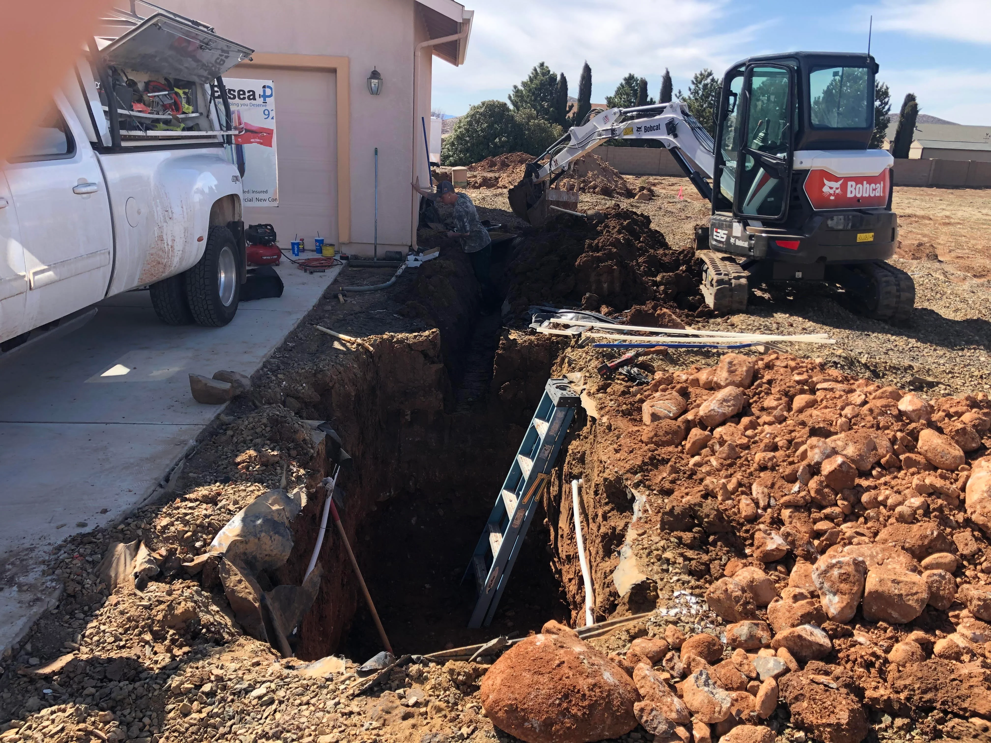 Septic system excavation with trenches, drainage rock, and mini excavator on-site