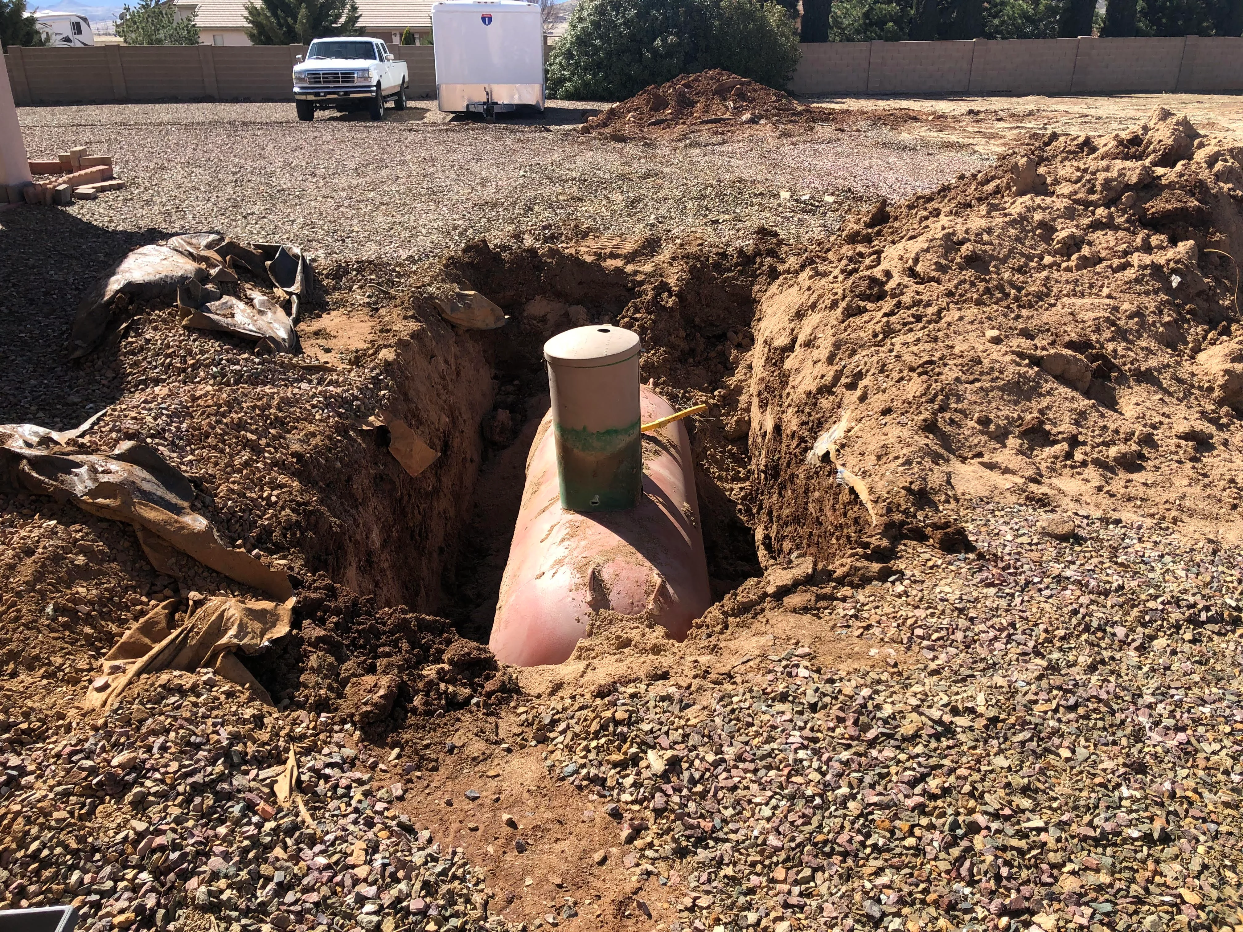 Underground propane tank installation in excavated pit with soil and gravel surrounding area
