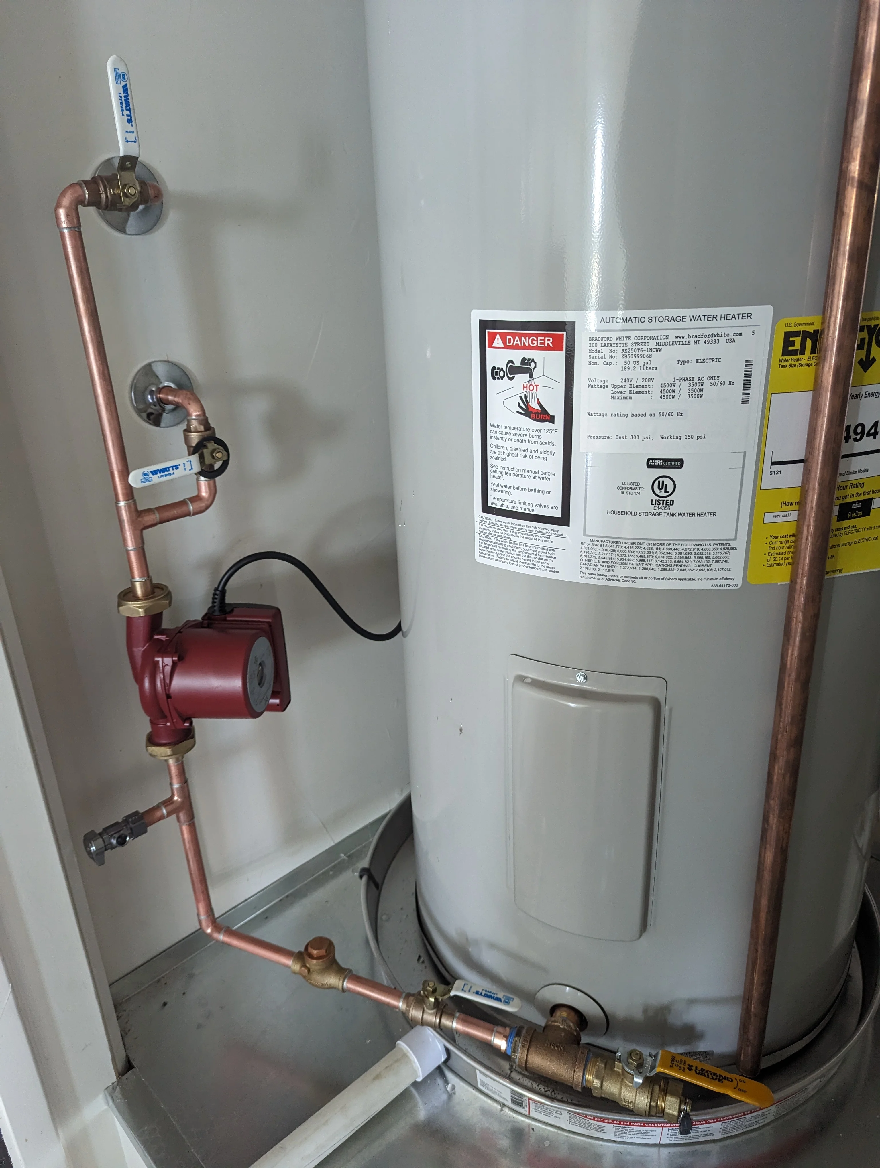 Water heater with copper piping, red circulation pump, and ball valves installed