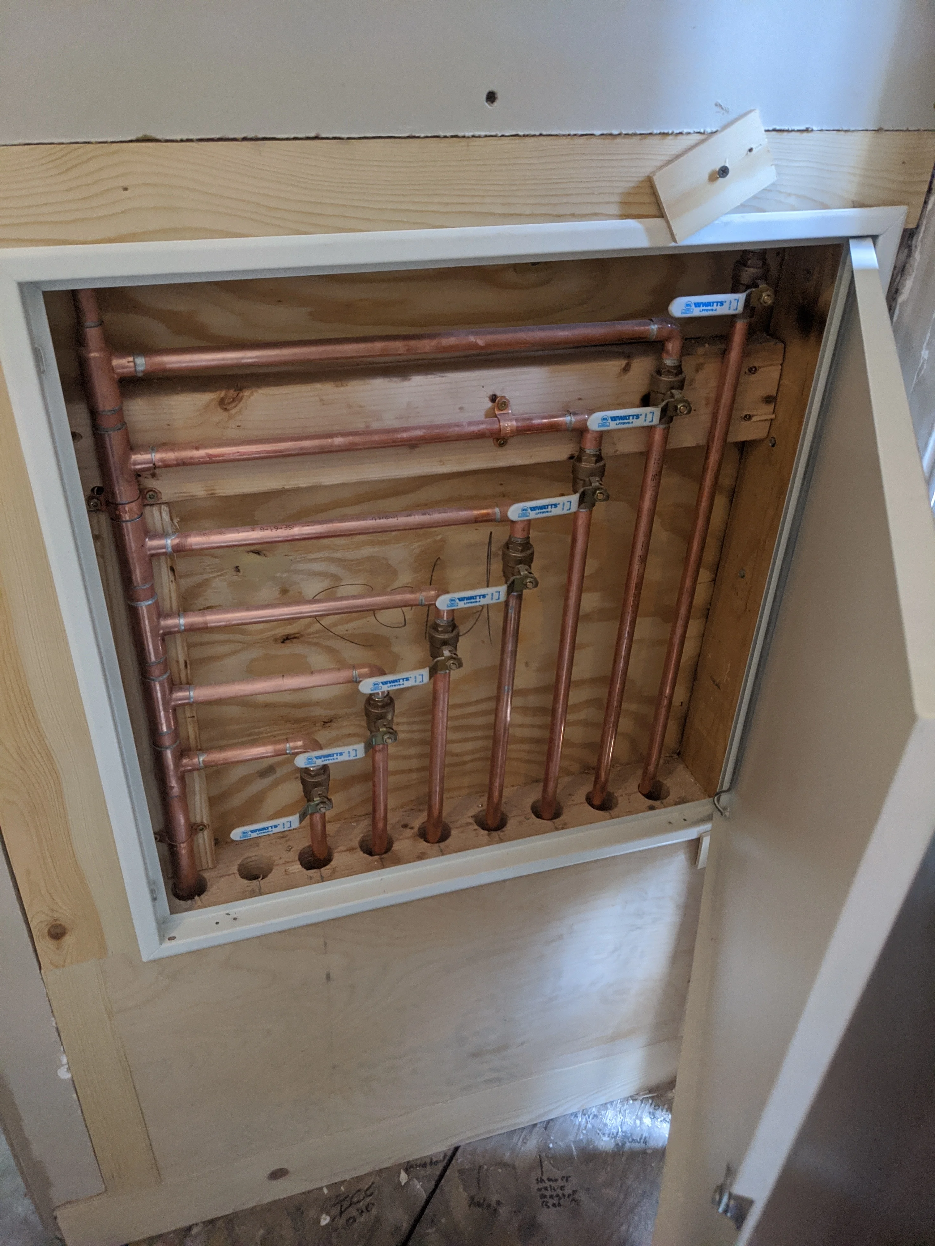 Copper plumbing rough-in with multiple supply lines, soldered fittings, and shutoff valves installed in wall framing